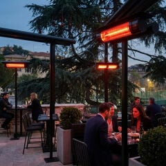 Kalabalık bir restoranın dış mekanında direklere monte edilmiş, IP67 su geçirmez özelliğiyle güvenli ısınma sağlayan ELCON RCH-2500/6 cihazları.