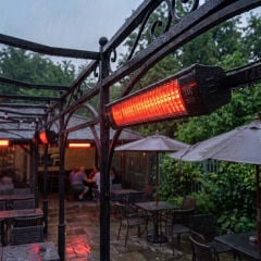 Yağmurlu havada klasik bir kafe terasına monte edilmiş, IP55 su korumalı aktif ELCON EIR-2000 ekonomik elektrikli infrared ısıtıcı.