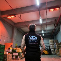 Ticari lojistik tesisinde tavana monte edilmiş, aktif olarak ortamı ısıtan ELCON EIR-TH-8 Infrared Fabrika Isıtıcısı sistemleri ve Elcon yetkilisi.